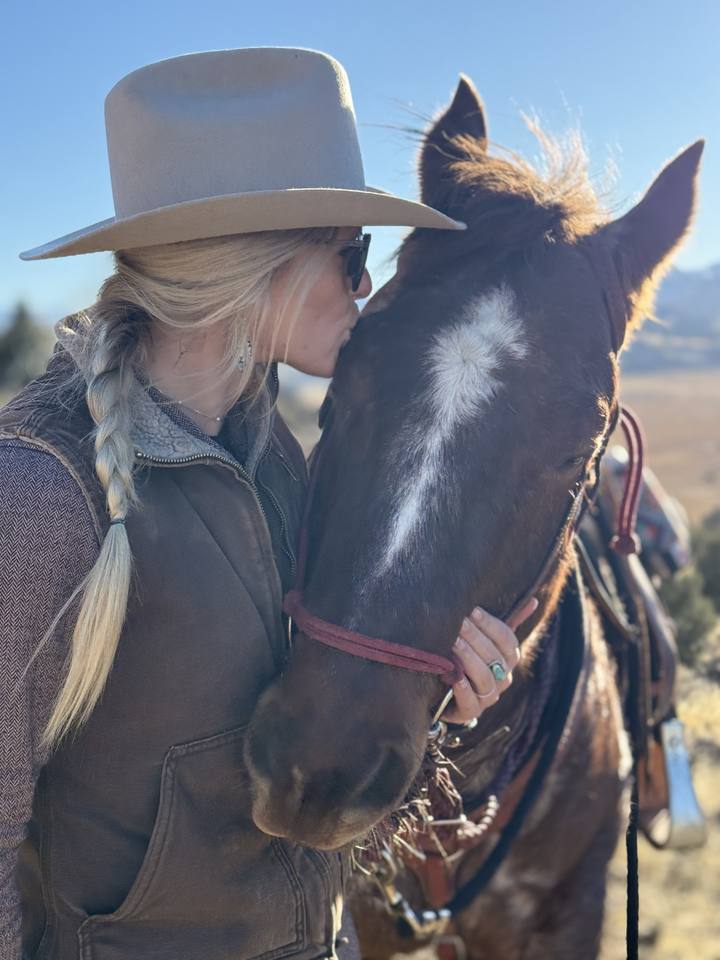 Kissing her bay horse on the forehead