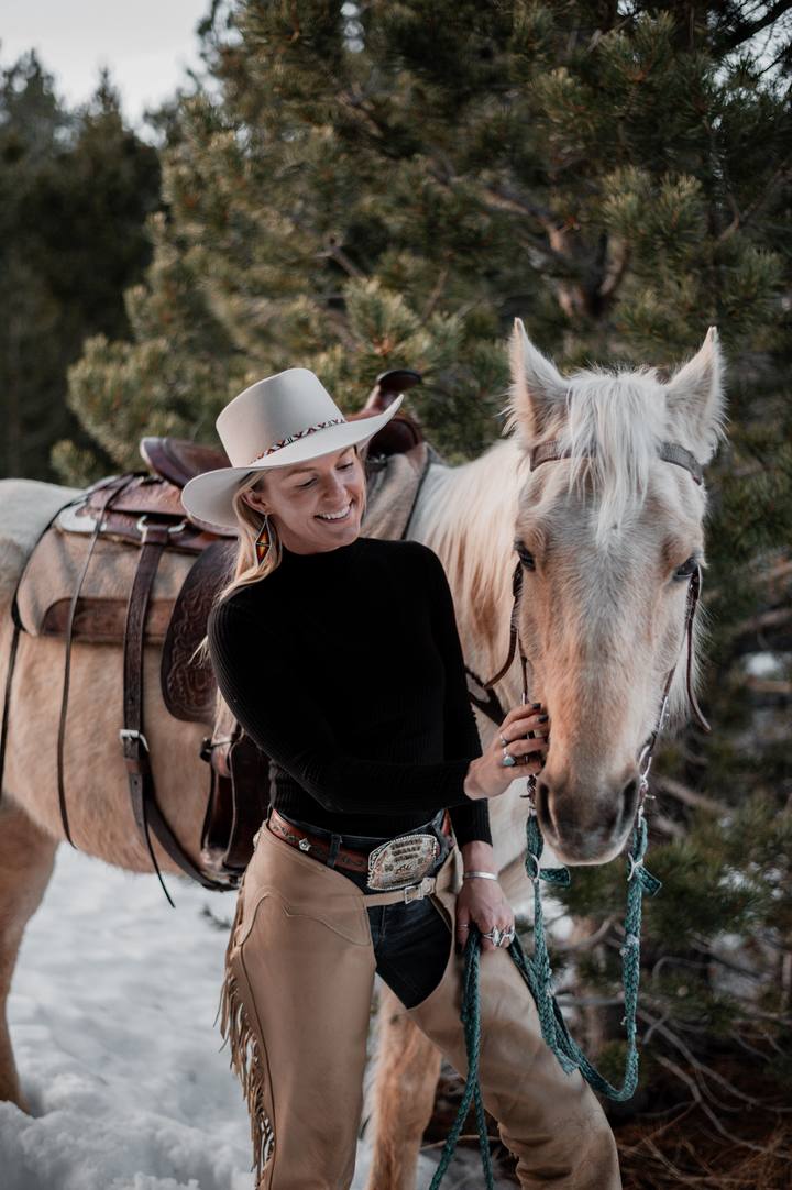 Outrider's founder smiling beside her saddled palomino in the snow